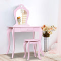 Pink vanity table with mirror and stool in a room setting with flowers and decor.